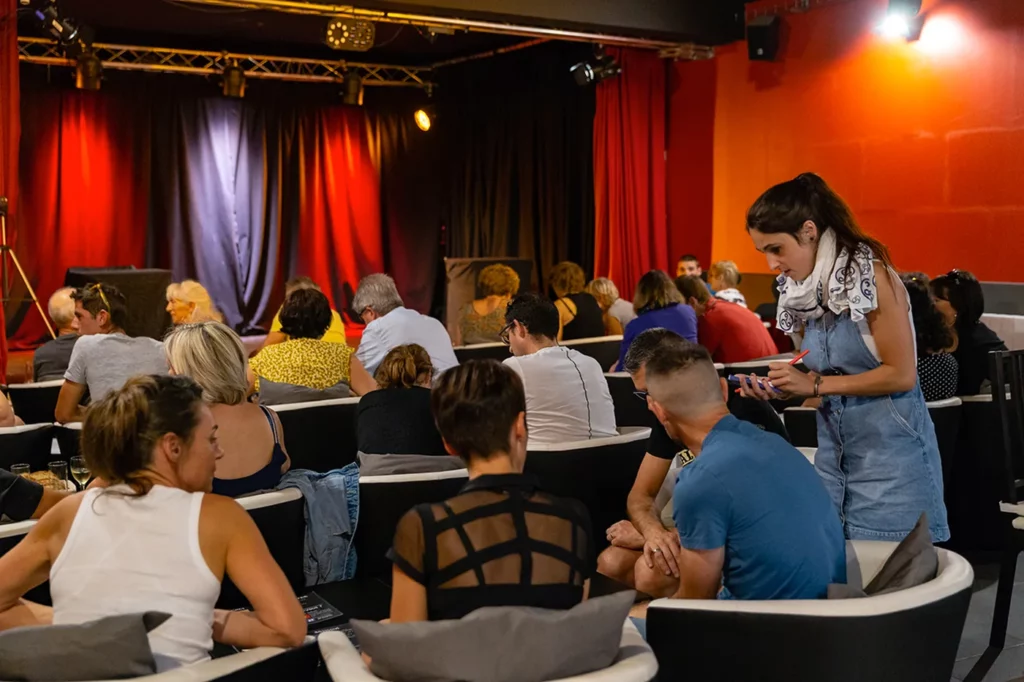 Public installé dans une salle de spectacle avant le début de la représentation.
